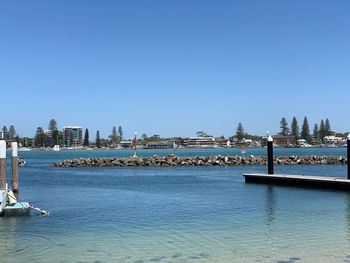 Sea by buildings against clear blue sky