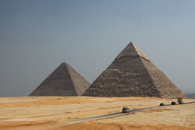 Cars on road by great pyramid of giza against sky