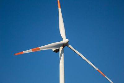 Low angle view of wind turbine against blue sky