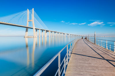 Pier over sea against clear blue sky