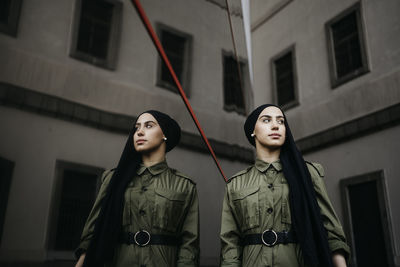 Portrait of young woman standing against building