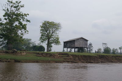 House by lake and trees against sky