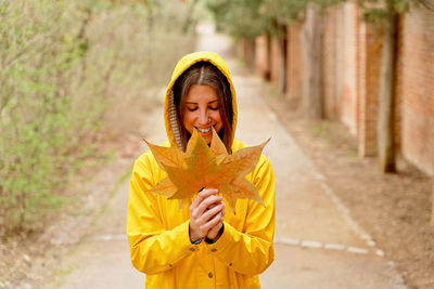 Smiling woman holding autumn leaf