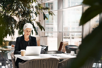 Mid section of woman using laptop on table