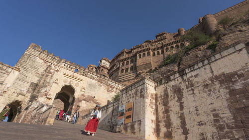 People at fort against clear blue sky