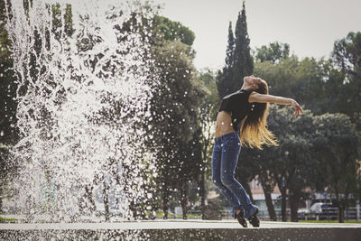 Full length of woman dancing against trees