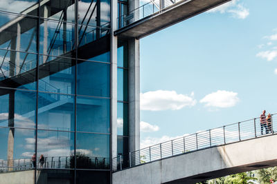 Man and woman walking on elevated walkway attached to modern building