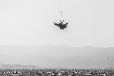 Low angle view of man hanging on rope against sky