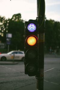 Illuminated stoplight on road against trees during sunset