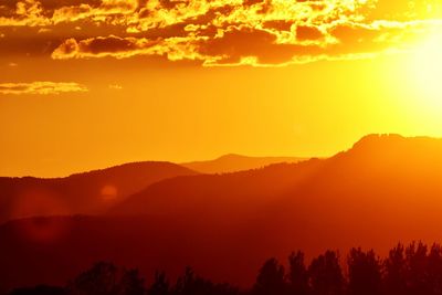 Scenic view of silhouette mountains against orange sky
