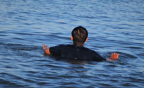 Rear view of man swimming in sea