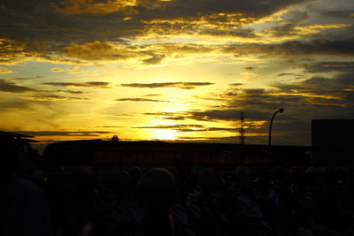 Silhouette people against dramatic sky during sunset