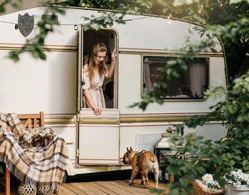 Camping and travelling . happy person relaxing outdoors near trailer. woman with dog is ready for