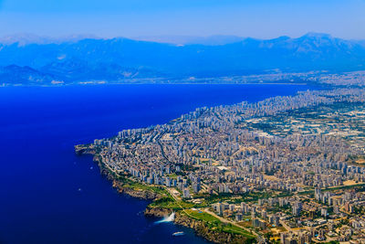 Aerial view of city by blue sea against mountains