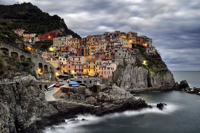 Cinque terre by sea against cloudy sky during sunset