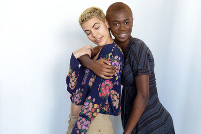 Cheerful lesbian couple embracing against white background