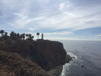 People standing on lighthouse by sea against sky