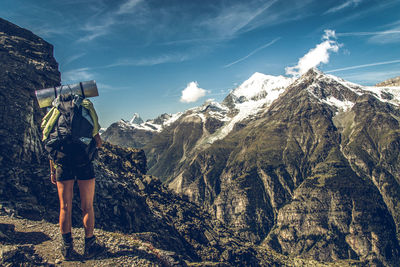 Rear view of man standing on mountain against sky