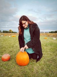 Full length of man with pumpkin on field against sky