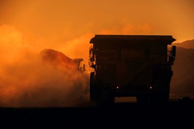 Construction truck against sky during sunset