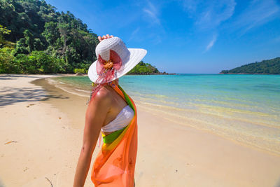 Woman standing at beach against sky