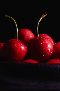 Close-up of wet cherries against black background