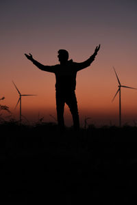 Silhouette man standing on field against sky during sunset