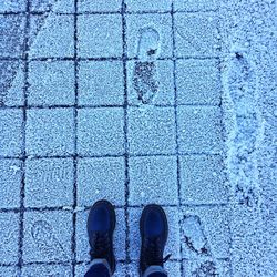 Low section of person standing on tiled floor during winter