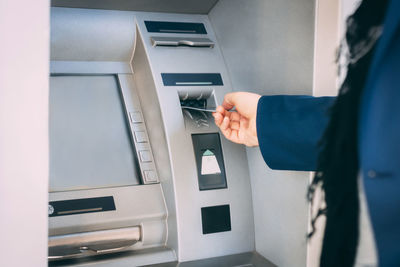 Cropped image of person using atm