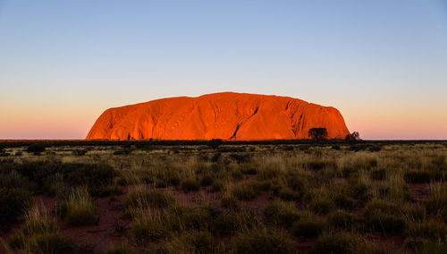 Rock formations on landscape against clear sky during sunset