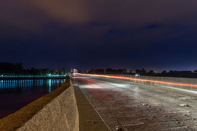 Light trails on road against sky at night