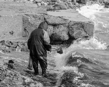 Full length rear view of worker cleaning beach