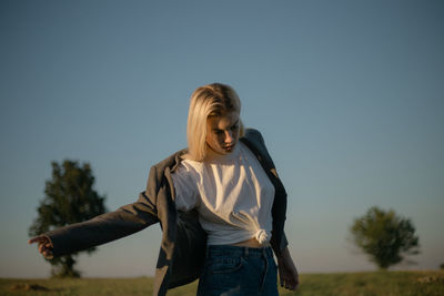 Happy woman standing on field against clear sky