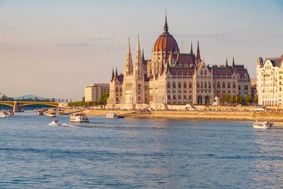 Hungarian parliament building by river against blue sky