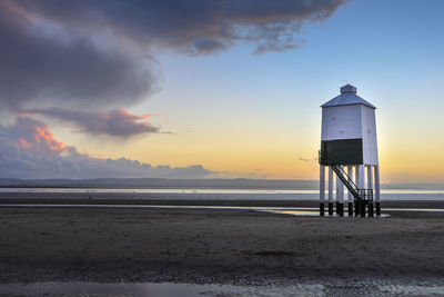 Lifeguard hut on beach against sky during sunset