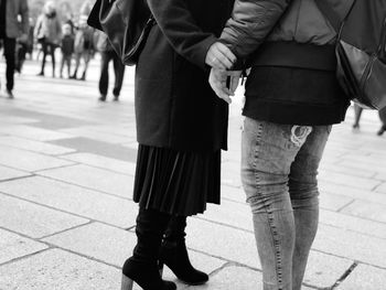 Low section of couple walking on footpath in city