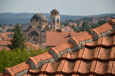 Part of tiled roof with roofs, houses and church in background