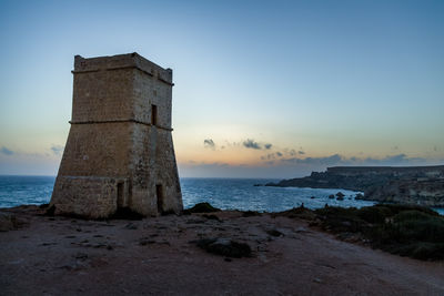 Lighthouse by sea against clear sky