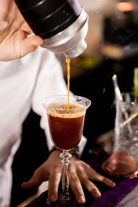 Midsection of man pouring drink on table