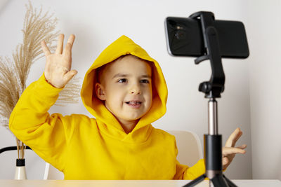 Adorable, cute, little boy blogger recording lifestyle blog, talking to camera of smartphone