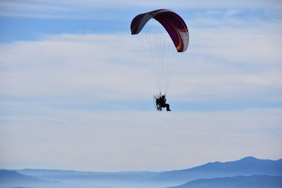 Low angle view of person paragliding against sky