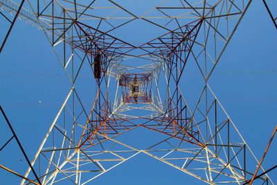 Low angle view of electricity pylon against clear blue sky