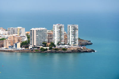 Buildings by sea against clear sky