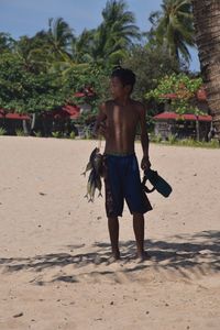 Rear view of shirtless man standing on beach