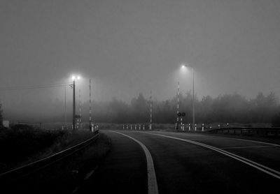 View of railroad tracks on road against sky during foggy weather