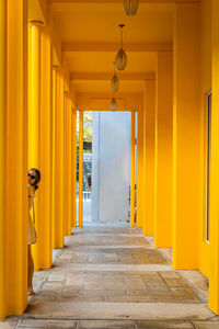 Woman standing amidst yellow columns in corridor