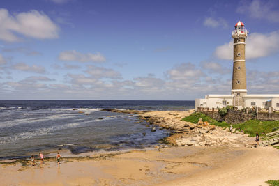 Lighthouse at beach against sky