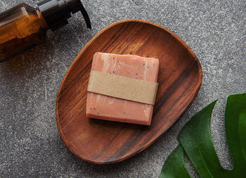 Handmade natural soap bar, massage oil and green leaf on a concrete background