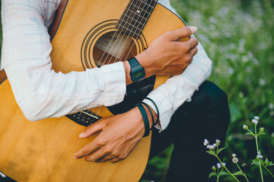 Midsection of man holding guitar in park