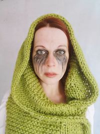 Portrait of woman wearing scarf with face paint against white background